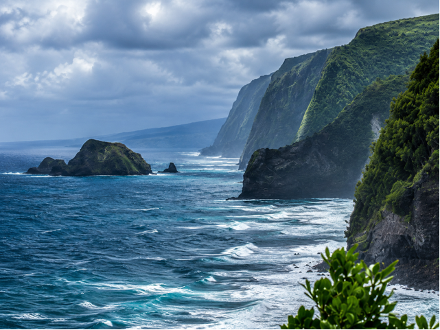 Dramatic green sea cliffs and surf along the Hawaiian coastline